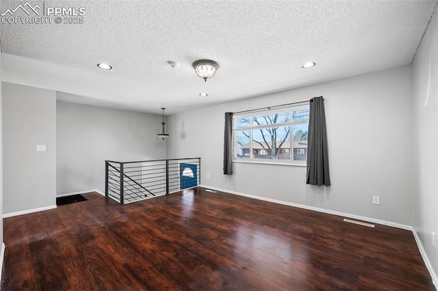 empty room featuring a textured ceiling and hardwood / wood-style floors