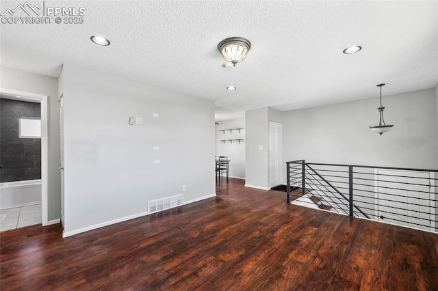 empty room featuring a textured ceiling and dark wood-type flooring