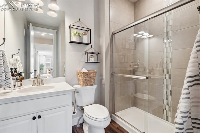 bathroom featuring toilet, vanity, walk in shower, and hardwood / wood-style floors