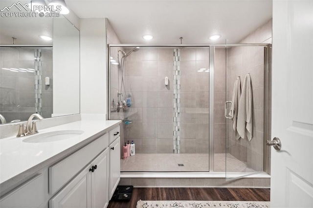 bathroom with a shower with door, vanity, and wood-type flooring