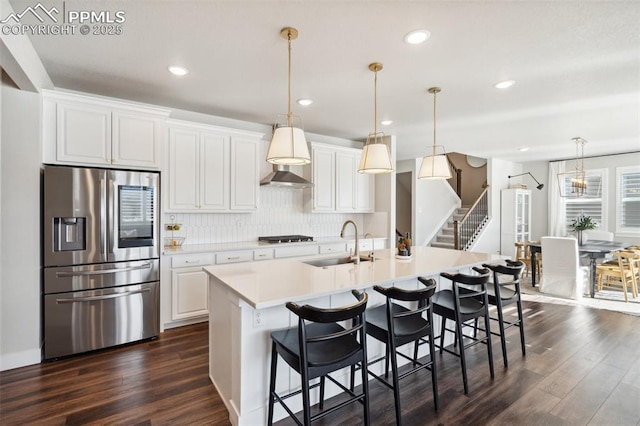 kitchen featuring white cabinets, a center island with sink, stainless steel refrigerator with ice dispenser, and sink