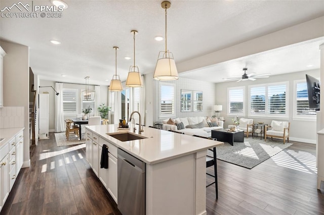 kitchen with dishwasher, a kitchen island with sink, sink, white cabinetry, and decorative light fixtures