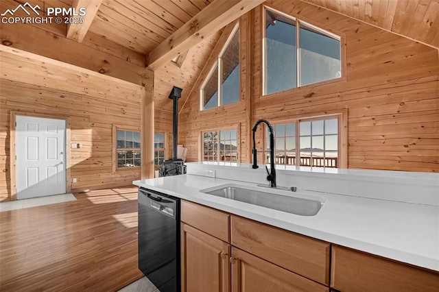 kitchen with sink, wooden walls, beamed ceiling, black dishwasher, and wood ceiling