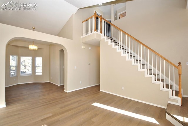 interior space with hardwood / wood-style flooring, a towering ceiling, and a chandelier