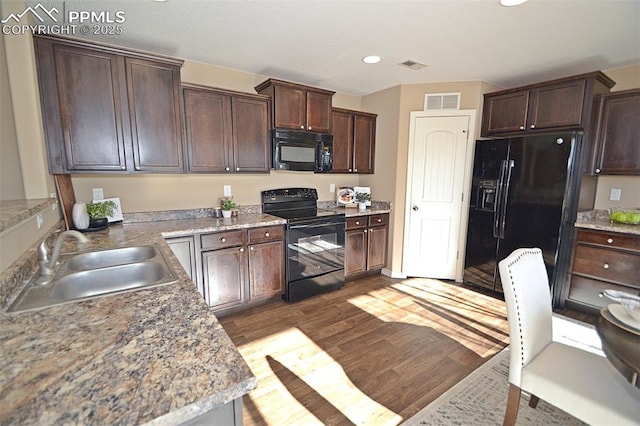 kitchen featuring dark brown cabinetry, sink, wood-type flooring, and black appliances