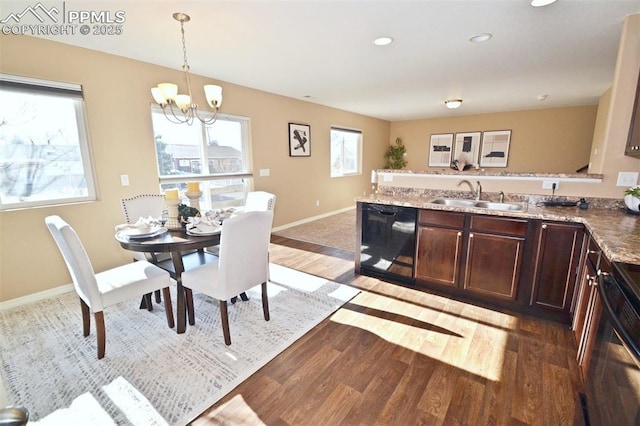 kitchen with pendant lighting, sink, dishwasher, dark brown cabinets, and dark hardwood / wood-style flooring