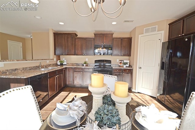 kitchen with sink, light stone counters, dark brown cabinetry, black appliances, and light wood-type flooring