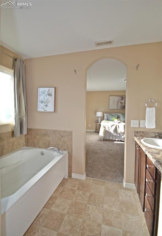 bathroom with vanity and a tub to relax in