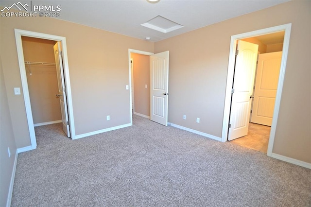 unfurnished bedroom with a spacious closet, light carpet, and a closet