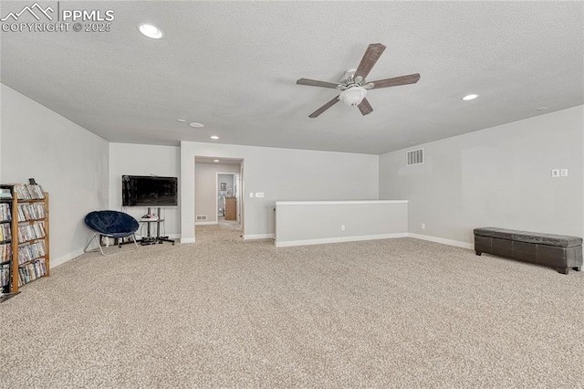 living room featuring ceiling fan, carpet floors, and a textured ceiling