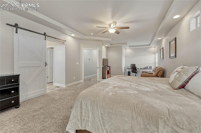 carpeted bedroom featuring a raised ceiling, a barn door, and ceiling fan