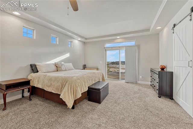 bedroom with access to outside, light colored carpet, ceiling fan, a raised ceiling, and a barn door