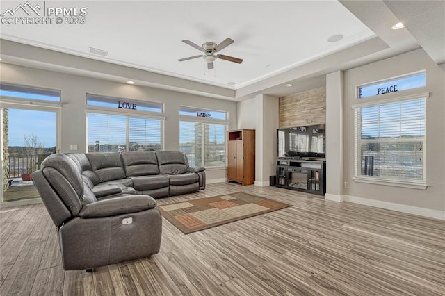 living room with a tray ceiling, light hardwood / wood-style flooring, and ceiling fan