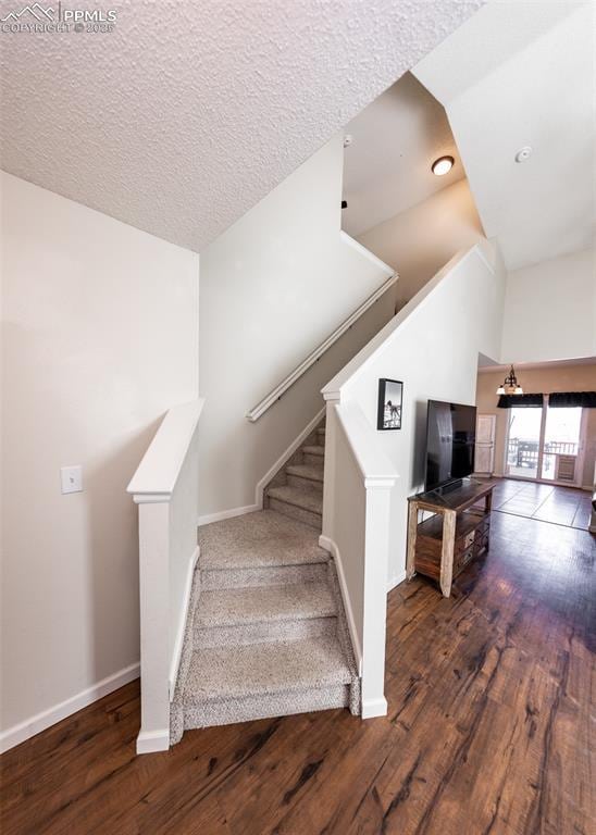 staircase featuring a textured ceiling, a towering ceiling, and hardwood / wood-style flooring