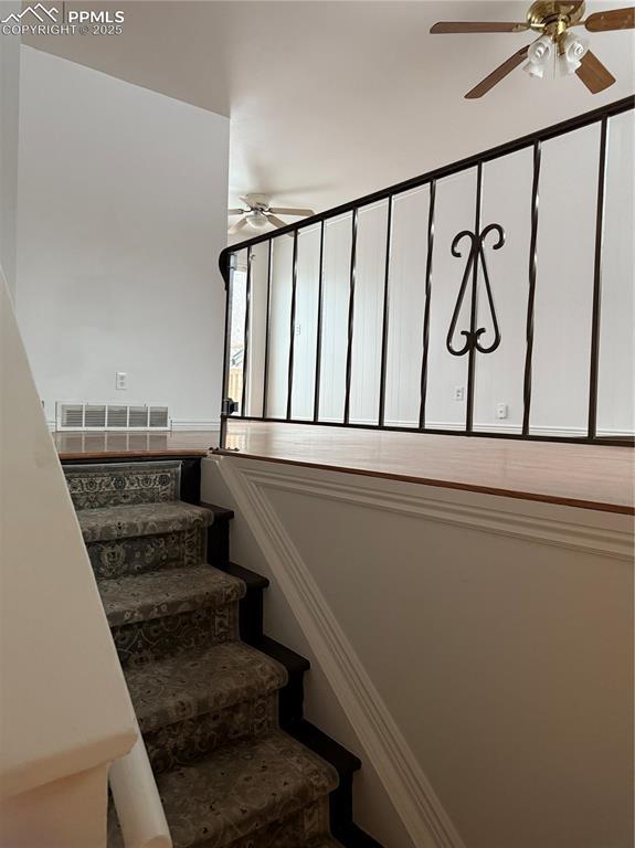 staircase featuring ceiling fan