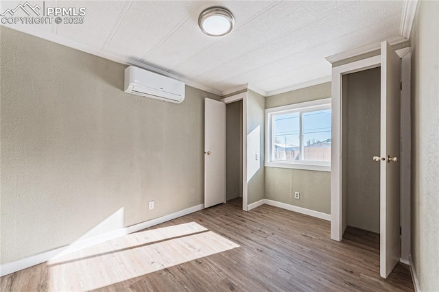 unfurnished bedroom featuring an AC wall unit, crown molding, and hardwood / wood-style floors