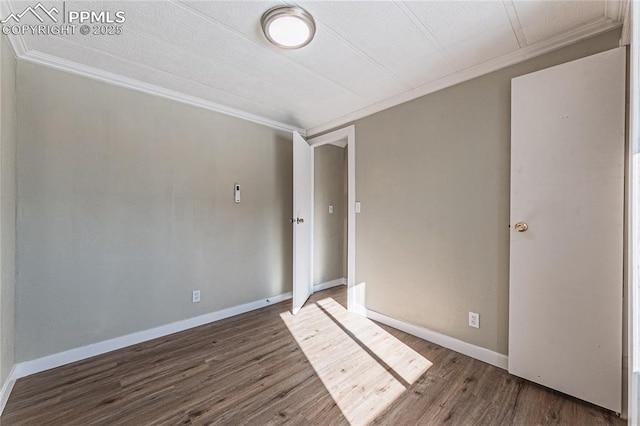 empty room featuring dark wood-type flooring and crown molding