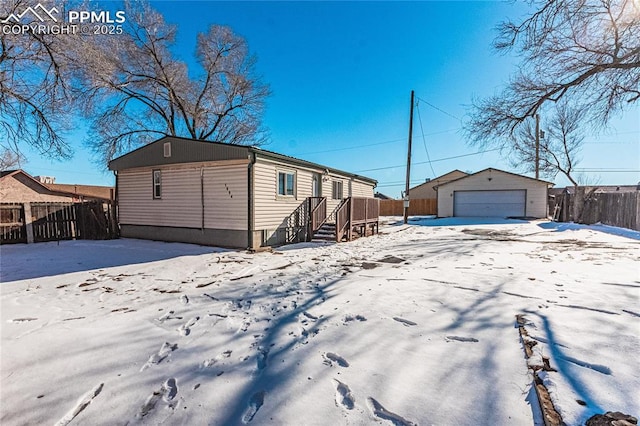 snow covered property with a garage and an outdoor structure