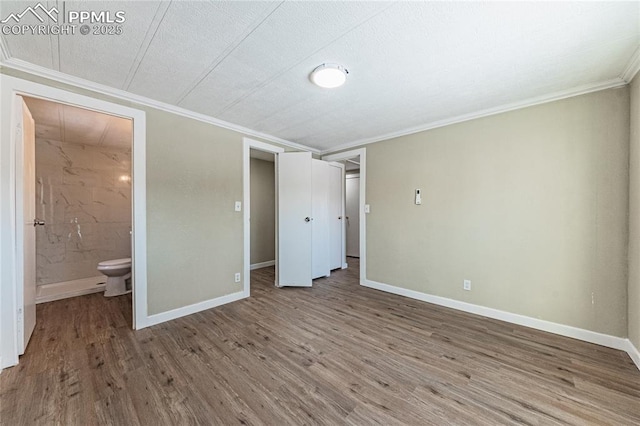 unfurnished bedroom with ensuite bathroom, a textured ceiling, ornamental molding, and hardwood / wood-style floors