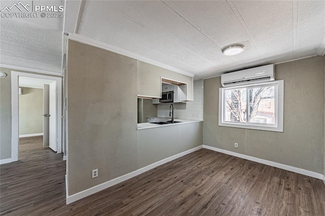 spare room with sink, an AC wall unit, a textured ceiling, and dark wood-type flooring