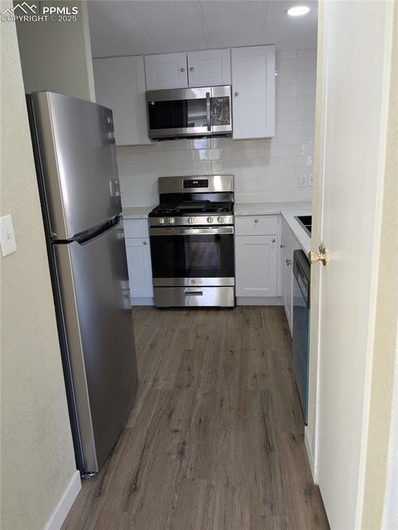 kitchen with stainless steel appliances, white cabinetry, dark hardwood / wood-style flooring, and tasteful backsplash