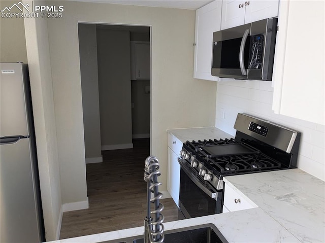 kitchen featuring backsplash, stainless steel appliances, white cabinets, and light stone counters