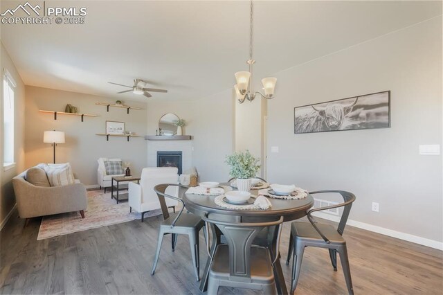 dining room featuring ceiling fan with notable chandelier and hardwood / wood-style floors