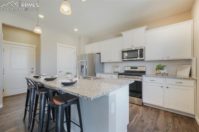 kitchen featuring stainless steel appliances, white cabinetry, and an island with sink