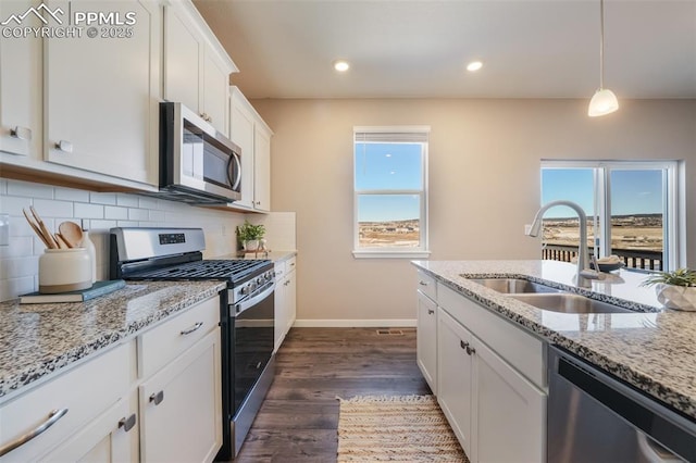 kitchen featuring white cabinetry, appliances with stainless steel finishes, decorative backsplash, decorative light fixtures, and sink