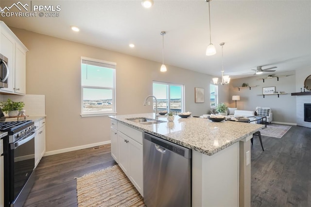 kitchen with ceiling fan, a center island with sink, sink, white cabinetry, and appliances with stainless steel finishes