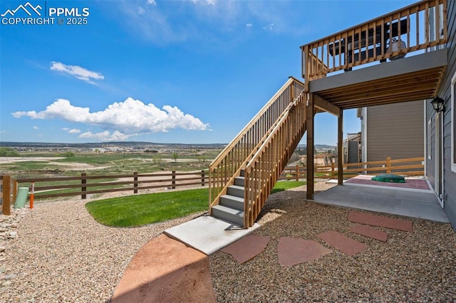 view of yard with a wooden deck, a rural view, and a patio