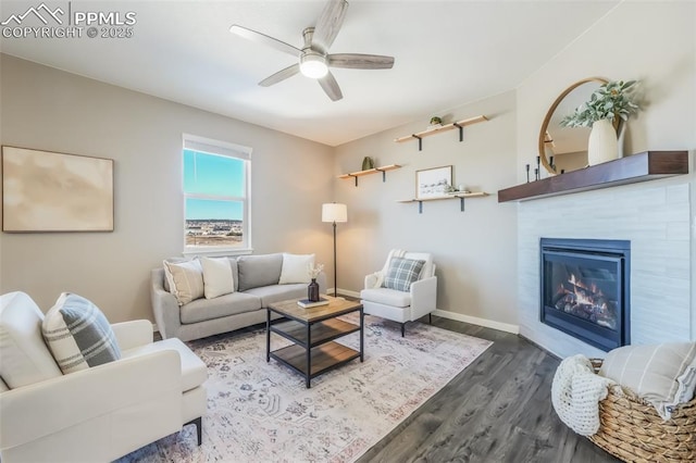 living room featuring a fireplace, ceiling fan, and dark wood-type flooring