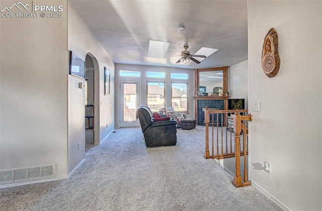 carpeted living room with a fireplace and ceiling fan