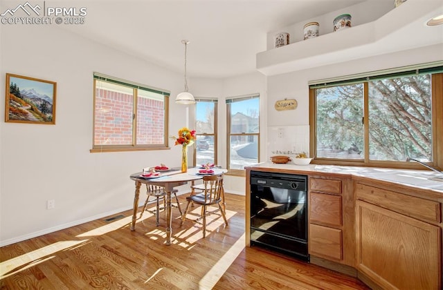 kitchen featuring sink, pendant lighting, black dishwasher, and light wood-type flooring