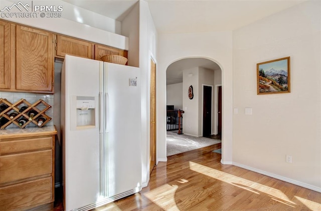 kitchen featuring hardwood / wood-style floors, decorative backsplash, and white refrigerator with ice dispenser