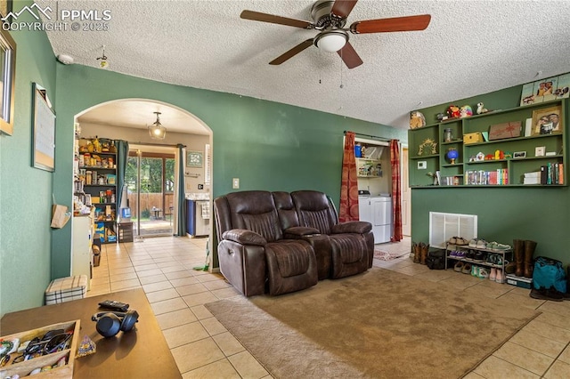 tiled living room with a textured ceiling, ceiling fan, and washer and clothes dryer