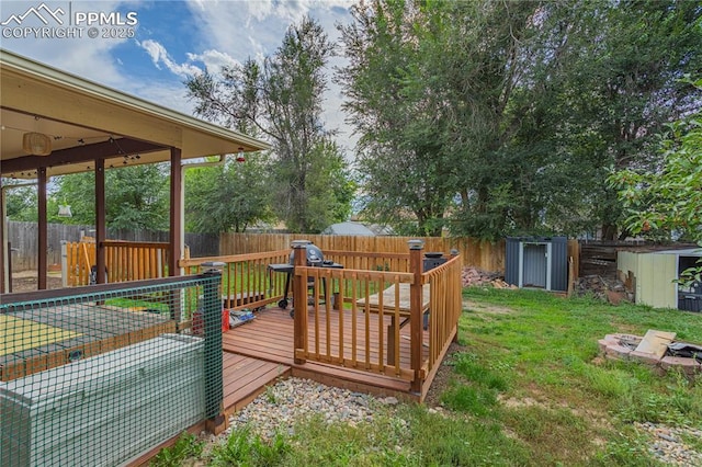 wooden terrace featuring a storage unit and a lawn