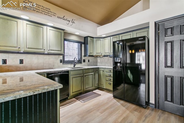 kitchen featuring black appliances, sink, decorative backsplash, green cabinetry, and light stone countertops