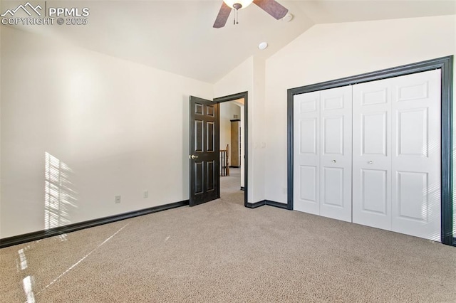 unfurnished bedroom featuring ceiling fan, light colored carpet, vaulted ceiling, and a closet