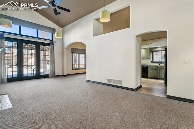 carpeted empty room with a wealth of natural light, high vaulted ceiling, french doors, and ceiling fan