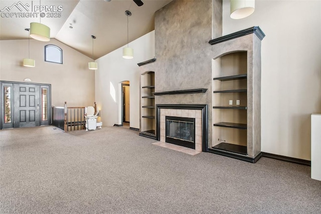 unfurnished living room featuring radiator heating unit, high vaulted ceiling, carpet floors, a tiled fireplace, and built in shelves