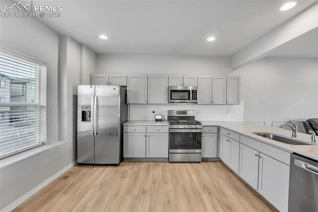 kitchen featuring stainless steel appliances, gray cabinetry, decorative backsplash, and sink