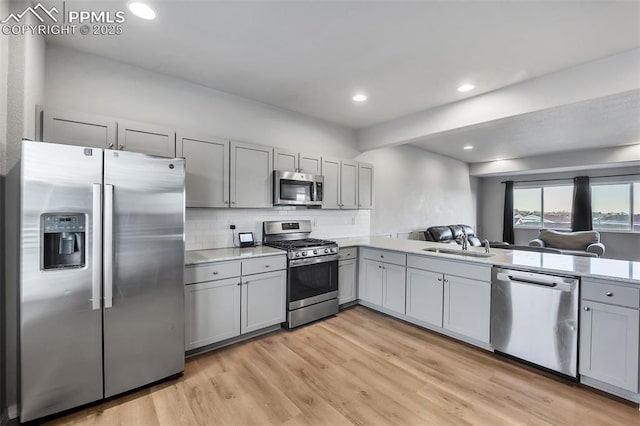 kitchen with stainless steel appliances, light hardwood / wood-style floors, tasteful backsplash, gray cabinets, and sink