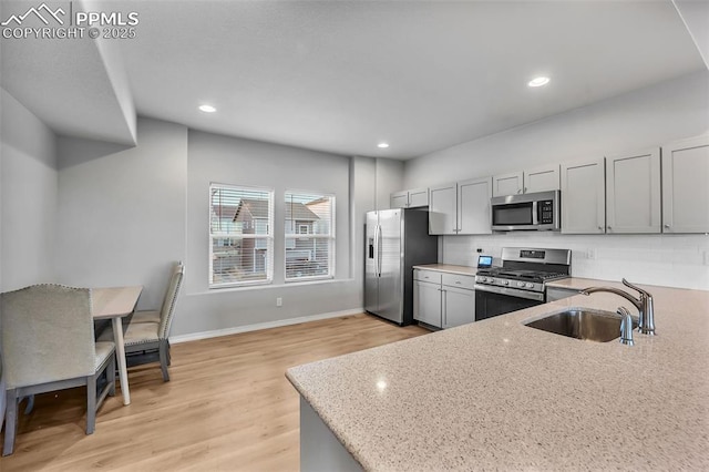 kitchen featuring light stone counters, appliances with stainless steel finishes, backsplash, and sink