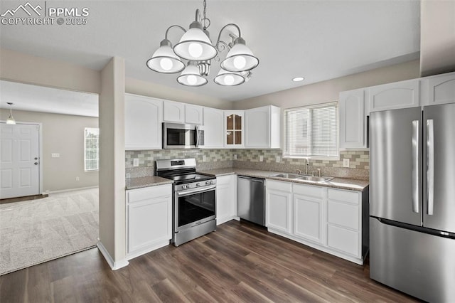 kitchen featuring sink, stainless steel appliances, white cabinetry, and decorative light fixtures