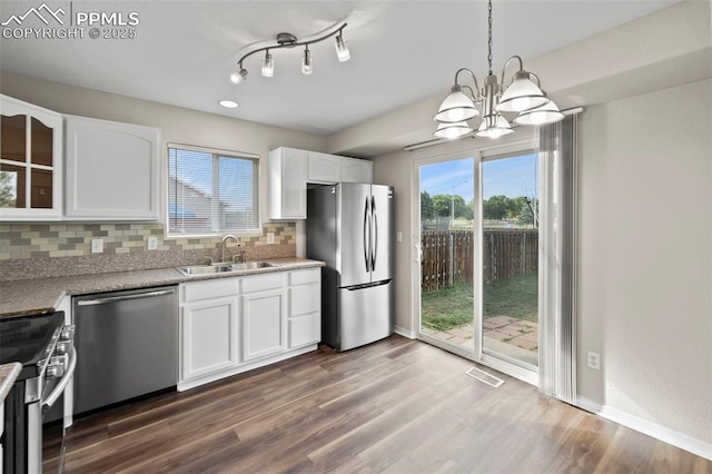 kitchen featuring decorative light fixtures, stainless steel appliances, backsplash, white cabinetry, and sink