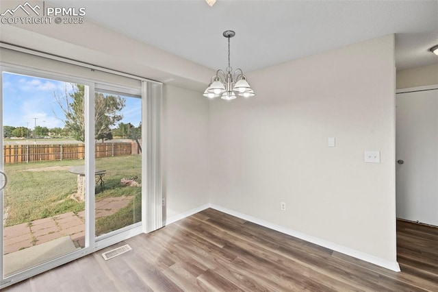 unfurnished dining area with a notable chandelier and wood-type flooring