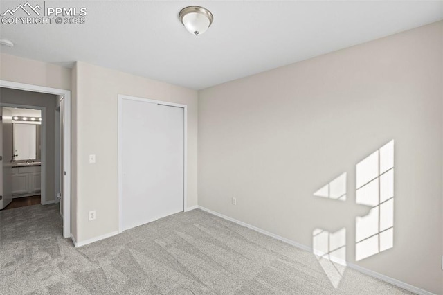 unfurnished bedroom featuring sink, light colored carpet, and a closet