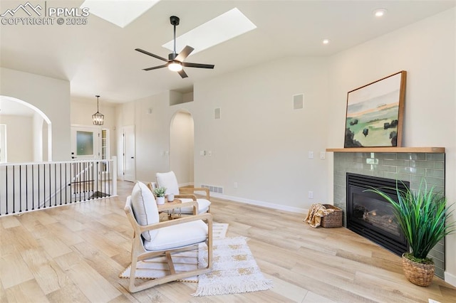 living area featuring ceiling fan, a skylight, and light hardwood / wood-style floors