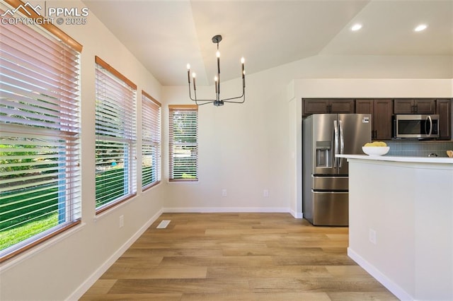 unfurnished dining area with light wood-type flooring, vaulted ceiling, and a chandelier